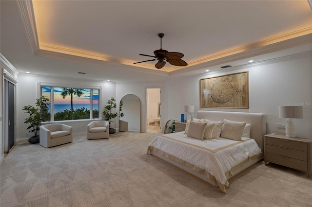 carpeted bedroom with a raised ceiling, ceiling fan, crown molding, and ensuite bathroom