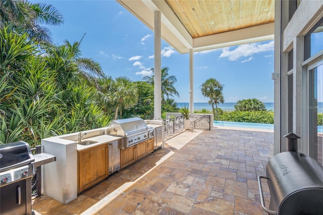 view of patio / terrace featuring area for grilling, a grill, a water view, and sink