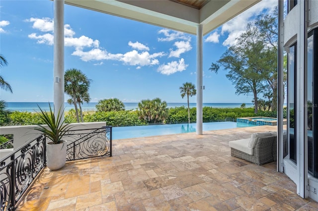 view of pool featuring a water view, an in ground hot tub, and a patio