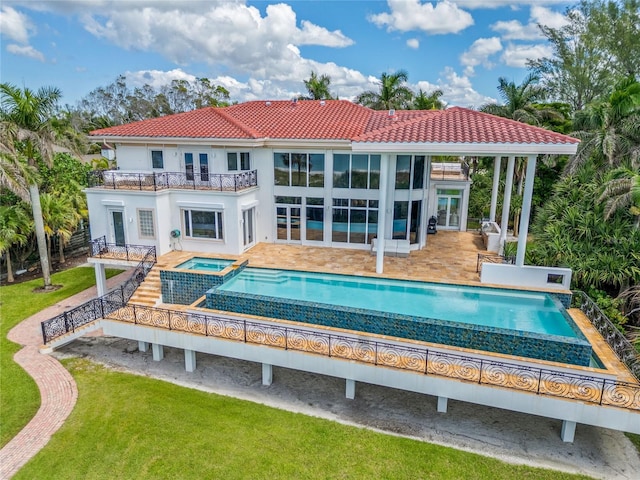 rear view of house featuring a swimming pool with hot tub, a balcony, a yard, and a patio area