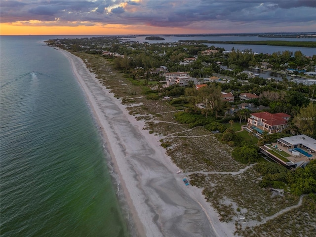 aerial view at dusk with a water view and a view of the beach