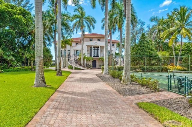 view of front of property with a front lawn and tennis court