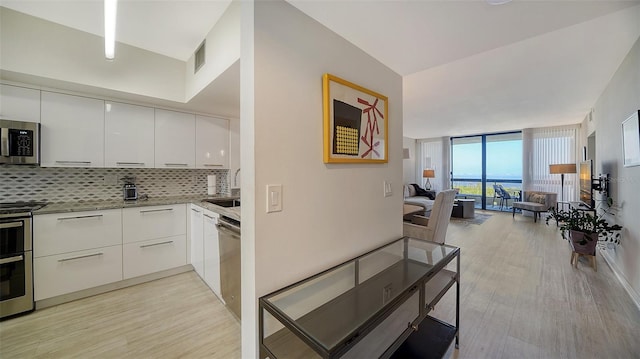 kitchen featuring stainless steel appliances, white cabinetry, sink, tasteful backsplash, and light wood-type flooring