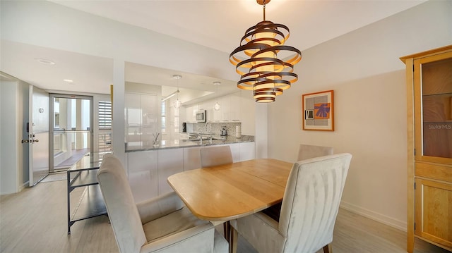 dining space featuring light hardwood / wood-style flooring and a chandelier