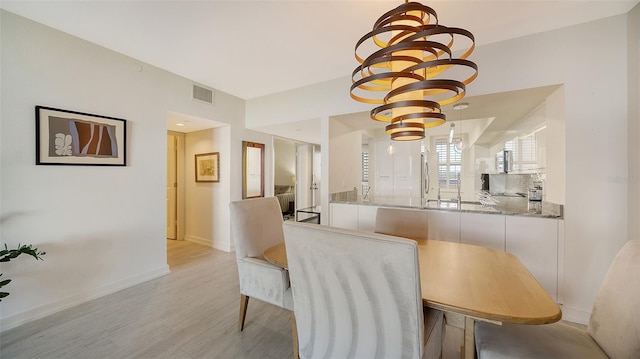 dining space with light hardwood / wood-style floors and a chandelier