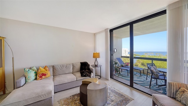 living room featuring a wall of windows, light hardwood / wood-style flooring, and a water view