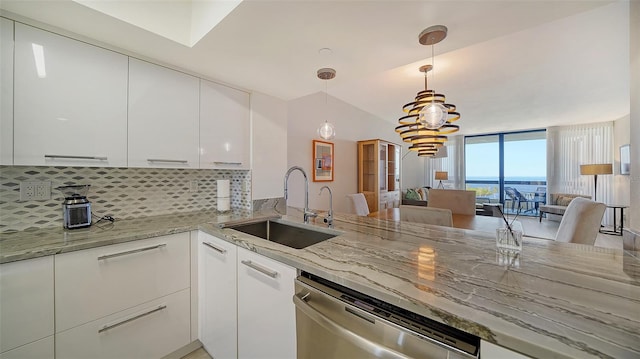 kitchen with white cabinets, light stone counters, stainless steel dishwasher, and sink