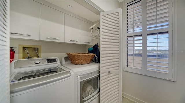 clothes washing area with washer and clothes dryer and cabinets