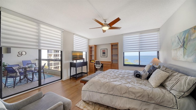 bedroom featuring hardwood / wood-style flooring, access to exterior, multiple windows, and ceiling fan