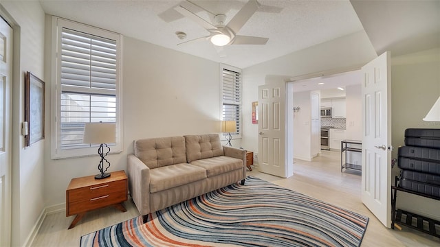 living room with a textured ceiling, ceiling fan, and light hardwood / wood-style flooring