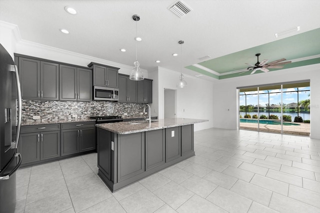 kitchen featuring appliances with stainless steel finishes, a center island with sink, hanging light fixtures, and sink