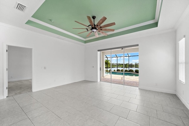 tiled spare room featuring a tray ceiling, ceiling fan, and ornamental molding