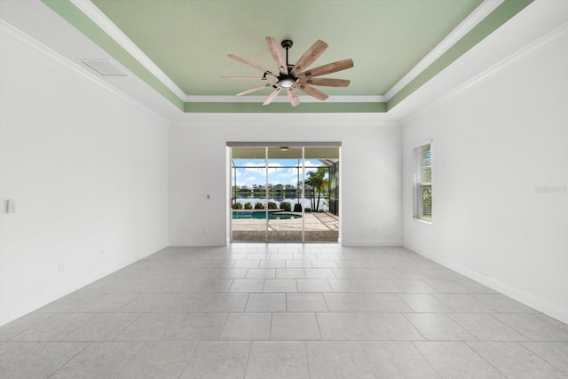 tiled spare room with a tray ceiling, ceiling fan, and ornamental molding