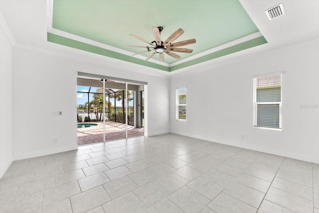 tiled spare room with a tray ceiling, ceiling fan, and crown molding