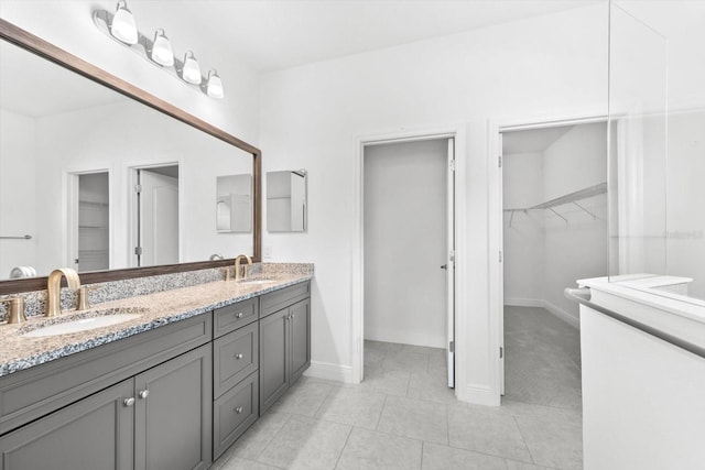 4704 Foxtail Dr, Parrish, FL 34219 - bathroom with double vanity, a walk in closet, tile patterned floors, and baseboards