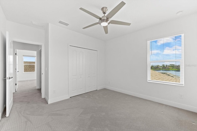 unfurnished bedroom with multiple windows, ceiling fan, a closet, and light colored carpet