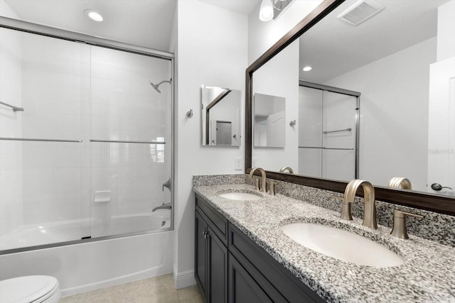 full bathroom with shower / bath combination with glass door, tile patterned floors, vanity, and toilet