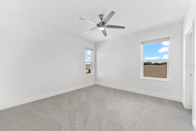 spare room featuring ceiling fan, light colored carpet, and a healthy amount of sunlight