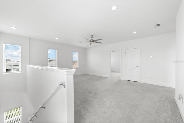 empty room featuring ceiling fan, light colored carpet, and a healthy amount of sunlight