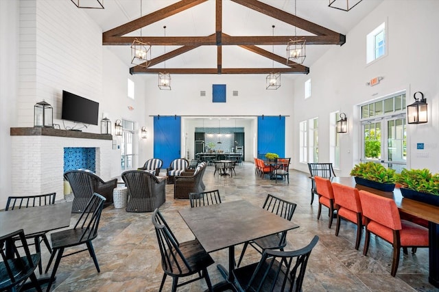 dining room with a barn door, beamed ceiling, and high vaulted ceiling