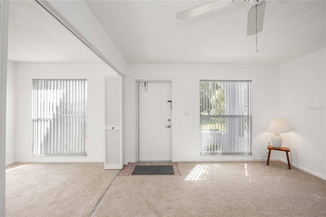 carpeted foyer with a textured ceiling and ceiling fan