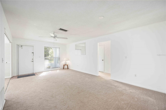 unfurnished room with a textured ceiling, light colored carpet, and ceiling fan