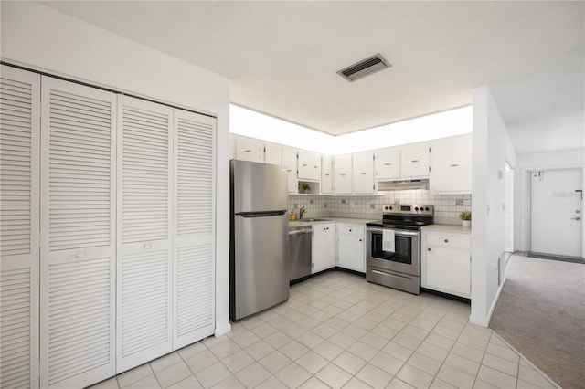 kitchen with white cabinets, light tile patterned floors, tasteful backsplash, sink, and appliances with stainless steel finishes