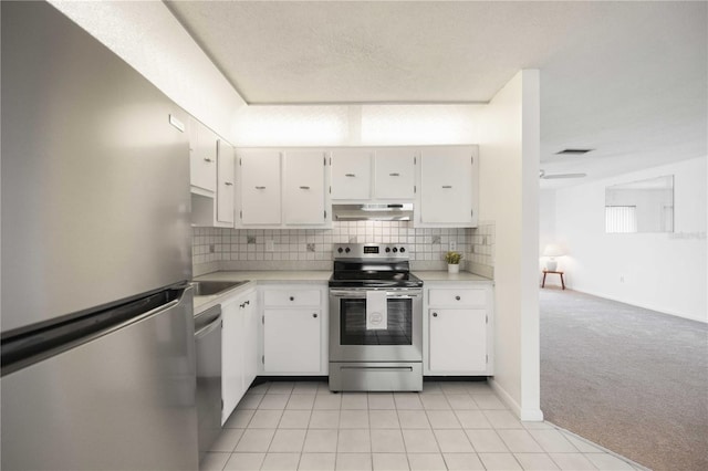 kitchen with appliances with stainless steel finishes, a textured ceiling, light carpet, decorative backsplash, and white cabinets