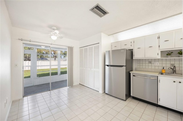 kitchen featuring stainless steel appliances, white cabinetry, sink, tasteful backsplash, and ceiling fan