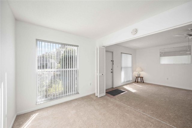 carpeted spare room featuring plenty of natural light and ceiling fan