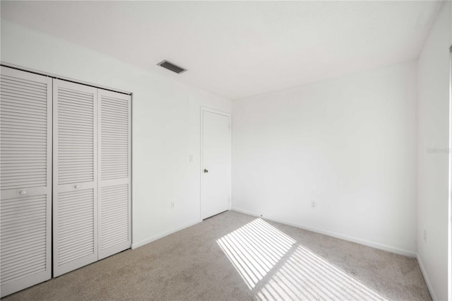 unfurnished bedroom with light carpet and a closet