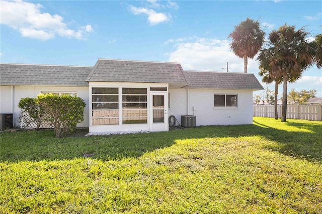 back of house with central AC, a sunroom, and a lawn