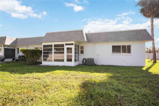 back of house with central AC unit, a lawn, and a sunroom