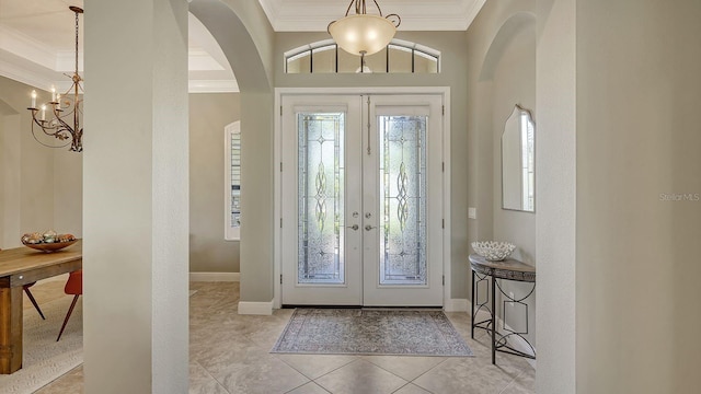 foyer with ornamental molding, french doors, light tile patterned floors, and an inviting chandelier