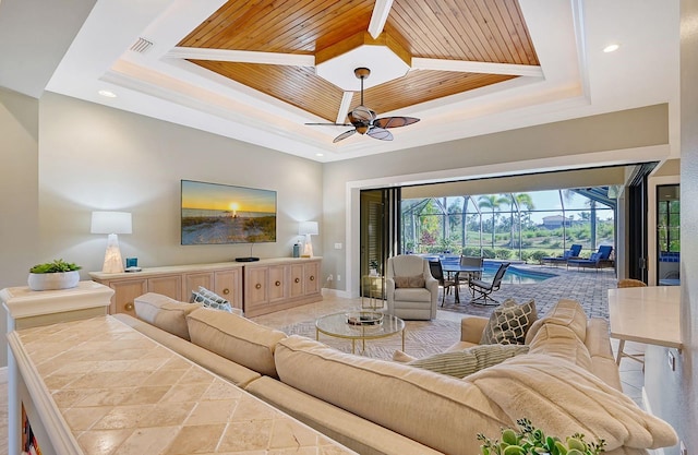 living room featuring ceiling fan, wood ceiling, and a tray ceiling