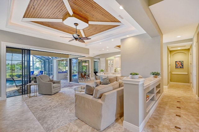 tiled living room featuring a tray ceiling, sink, wooden ceiling, and ceiling fan