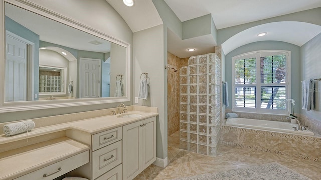 bathroom featuring independent shower and bath, vanity, vaulted ceiling, and tile patterned floors