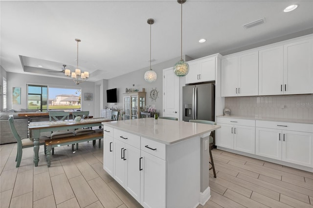 kitchen with white cabinetry, a center island, stainless steel fridge, and decorative light fixtures