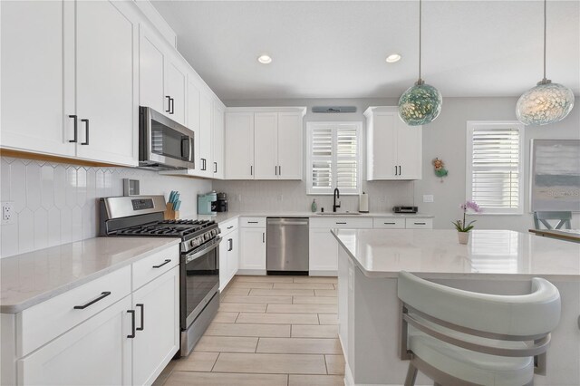 kitchen featuring stainless steel appliances, sink, a breakfast bar, and pendant lighting