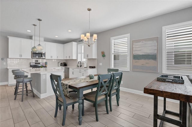 dining space with an inviting chandelier, sink, and light hardwood / wood-style floors