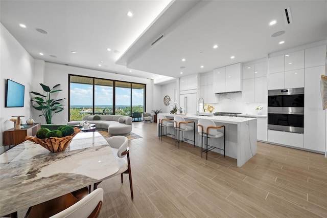 kitchen featuring white cabinets, sink, a breakfast bar area, an island with sink, and appliances with stainless steel finishes