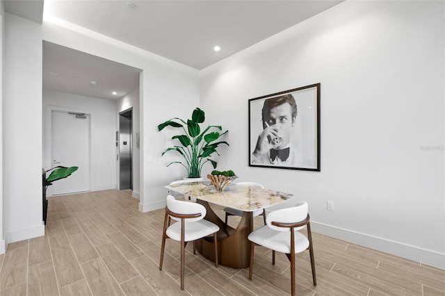 dining area with elevator and light hardwood / wood-style flooring