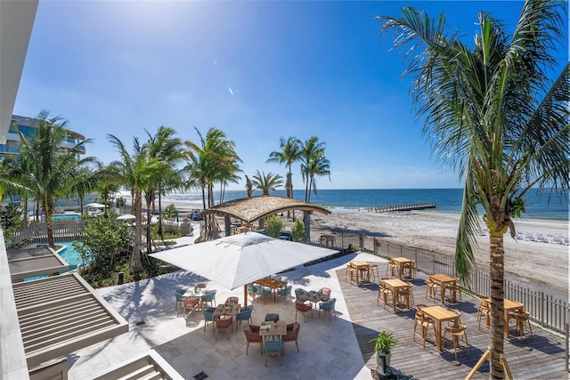 view of patio featuring a community pool, a water view, and a view of the beach