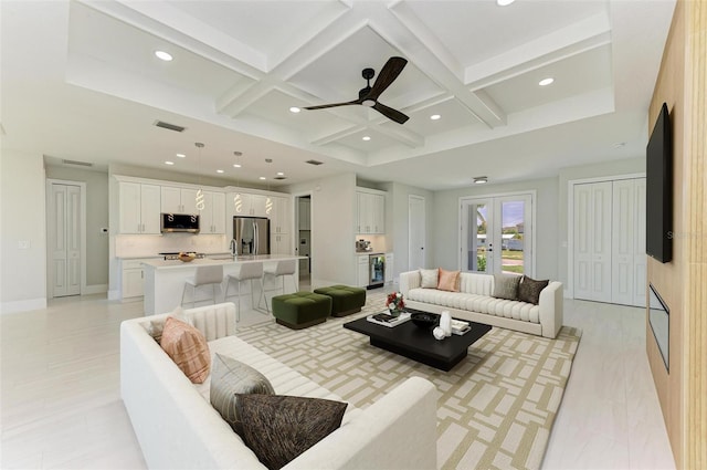 living room with ceiling fan, beam ceiling, and coffered ceiling