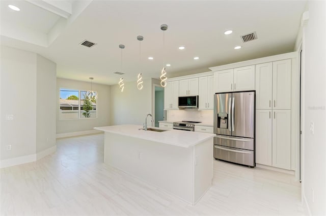 kitchen featuring a center island with sink, stainless steel appliances, backsplash, hanging light fixtures, and white cabinets