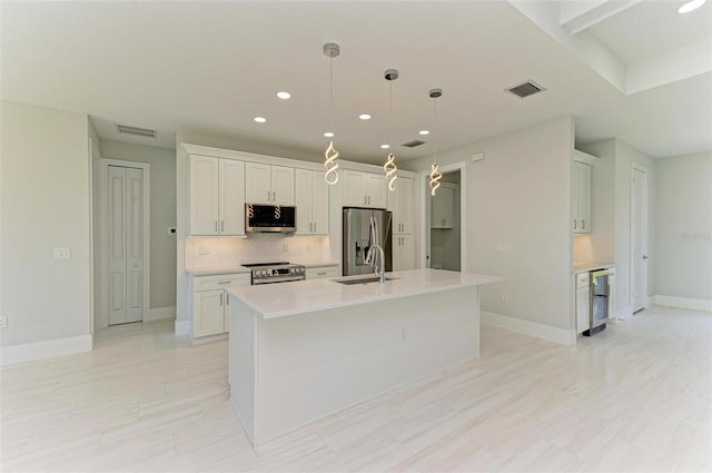 kitchen featuring white cabinets, appliances with stainless steel finishes, and a center island with sink