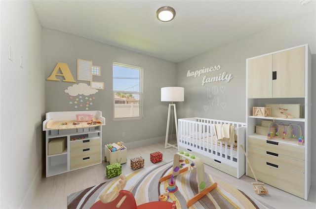 bedroom with a crib and light hardwood / wood-style floors