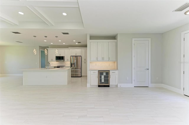 kitchen with appliances with stainless steel finishes, backsplash, wine cooler, white cabinets, and decorative light fixtures