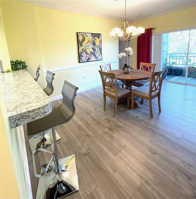 dining space featuring a textured ceiling, a notable chandelier, ornamental molding, and light hardwood / wood-style flooring