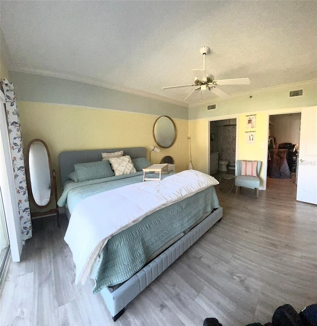 bedroom with hardwood / wood-style flooring, a textured ceiling, ceiling fan, a closet, and a walk in closet